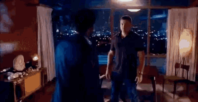 two men are standing next to each other in a living room .