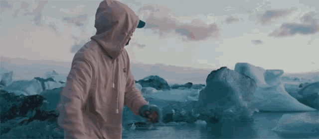 a man in a hoodie is standing in front of a body of water .