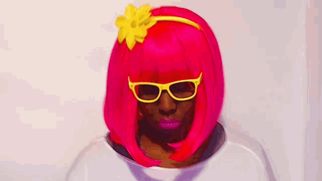 a woman wearing a bright pink wig and yellow sunglasses