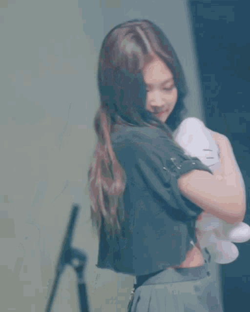 a girl in a black crop top is holding a hello kitty stuffed animal