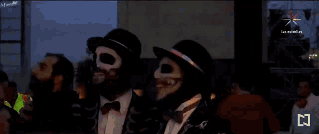 a group of people dressed in skeleton costumes are standing in front of a screen that says las estrellas