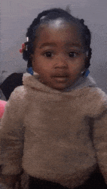 a little girl wearing a white sweater and black pants is smiling and looking at the camera .