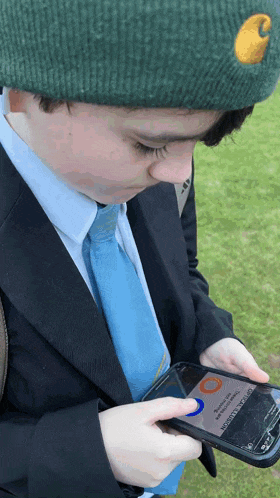 a boy in a suit and tie is looking at a cell phone that says emergency assistance on the screen