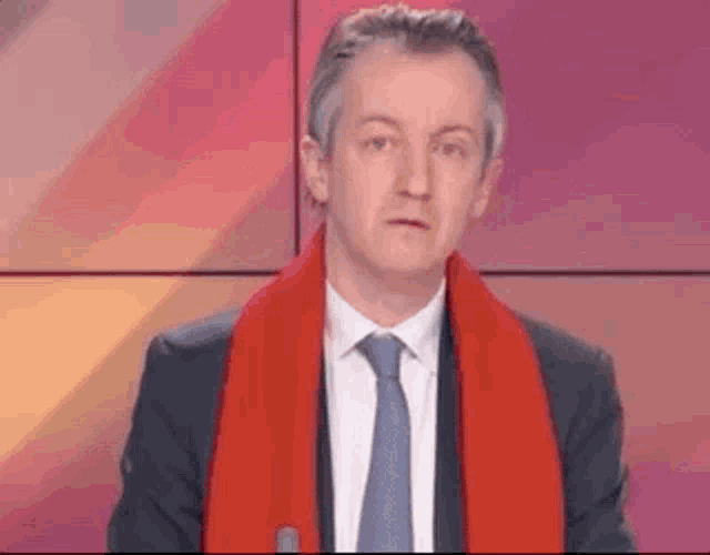 a man in a suit and tie is wearing a red scarf .