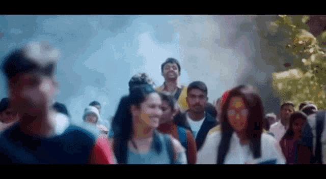 a large group of people are walking down a street in a blurry photo .