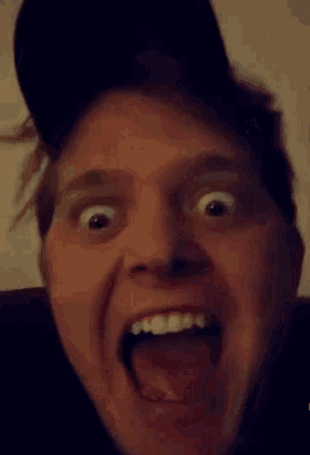a man wearing a baseball cap is making a funny face with his tongue out .
