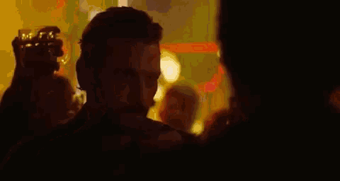 a man with a beard is talking to another man in a crowded room .