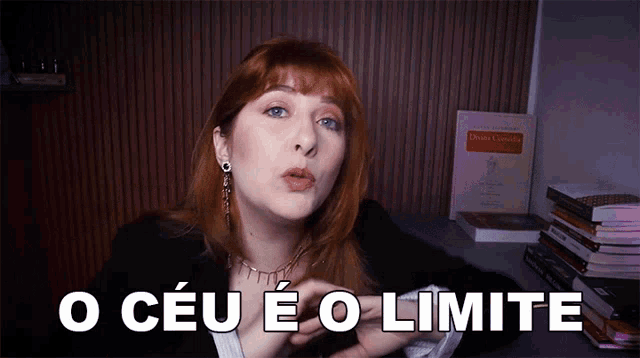 a woman with red hair says o ceu e o limite in front of a stack of books