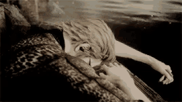 a black and white photo of a woman laying on a couch in the water .