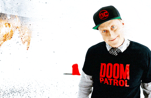 a man wearing a doom patrol shirt and a hat
