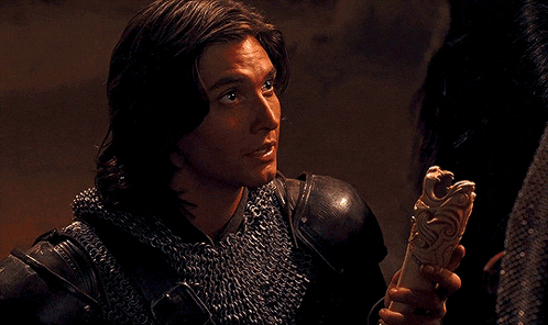 a man in chain mail is holding a piece of wood