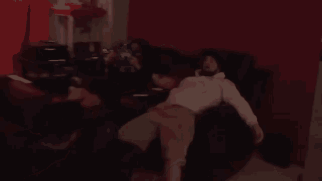 a man is laying on a couch in a dark room watching a movie .