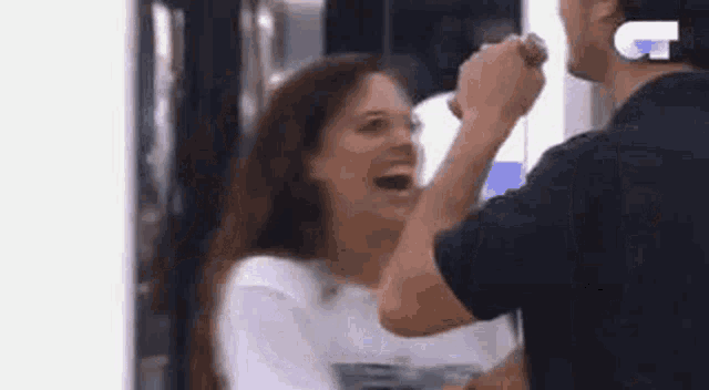 a man is holding a woman 's hand in front of her face while she laughs .