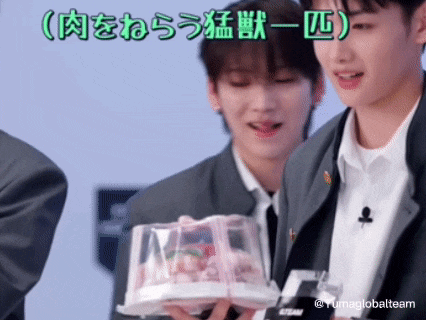 a man in a suit is holding a cake in a plastic container with chinese writing on it