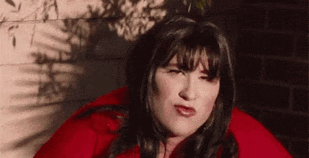 a woman in a red jacket is making a funny face .