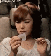 a woman is sitting in a car seat holding a piece of paper in her mouth .
