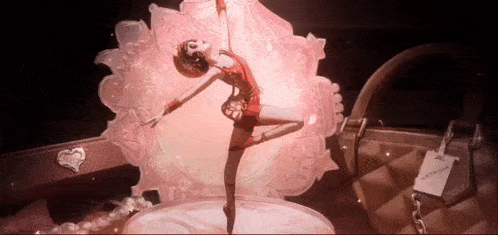 a ballerina is dancing in front of a pink purse
