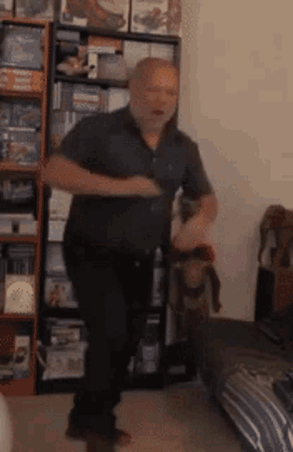 a man is dancing in a living room in front of a bookshelf filled with books