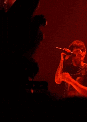 a man is singing into a microphone in front of a red background