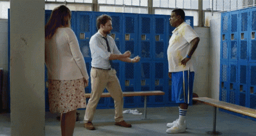 a man in a white shirt and blue shorts is standing in a locker room