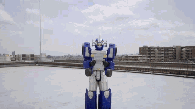a blue and silver robot stands on a rooftop