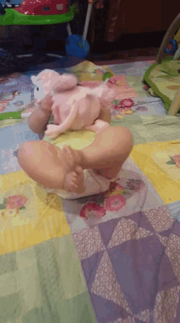 a baby laying on a blanket with a stuffed animal