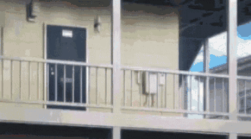 a building with a balcony and a door with a sign on it