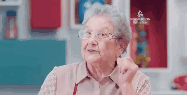 an elderly woman wearing glasses is making a funny face while sitting in a kitchen .