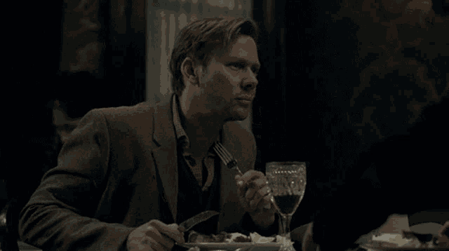 a man in a suit is sitting at a table eating a meal