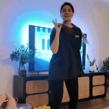 a woman in a black shirt is dancing in a living room