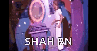 a little girl is standing in front of a vanity with the words shah rn on it .