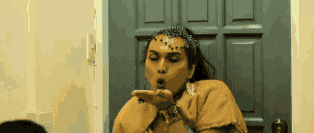 a woman blowing a kiss while wearing a headpiece