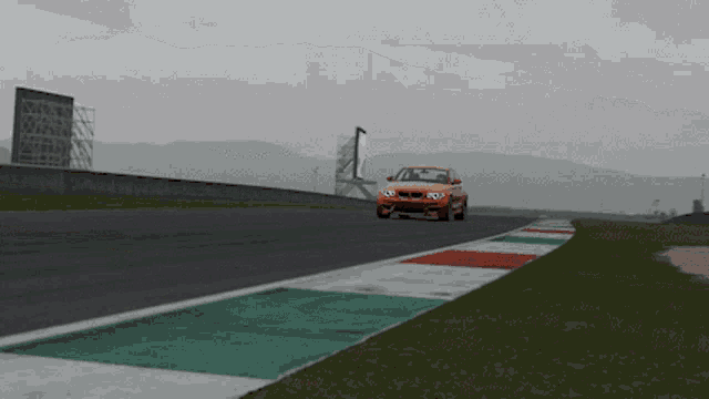 an orange car is driving on a race track with mountains in the background