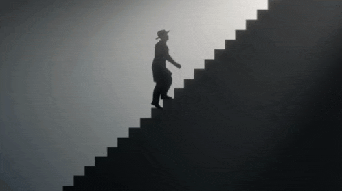 a man in a hat is walking up a set of stairs .