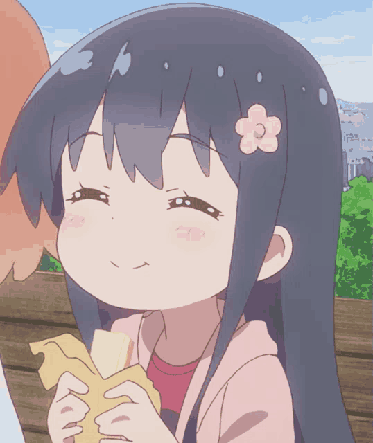 a girl with a flower in her hair is smiling and eating a sandwich
