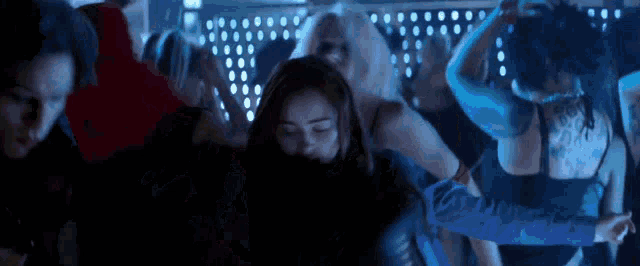 a group of people are dancing in a dark room .