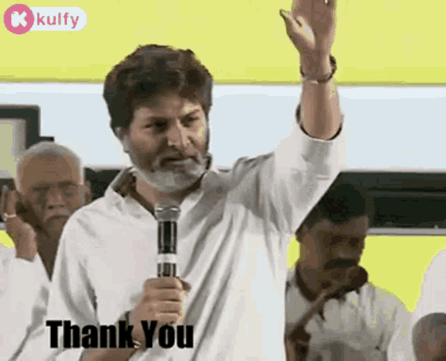 a man with a beard is holding a microphone in front of a crowd and saying thank you .