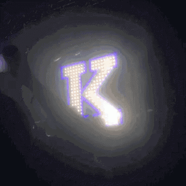 the letter k is glowing in the dark with a purple background