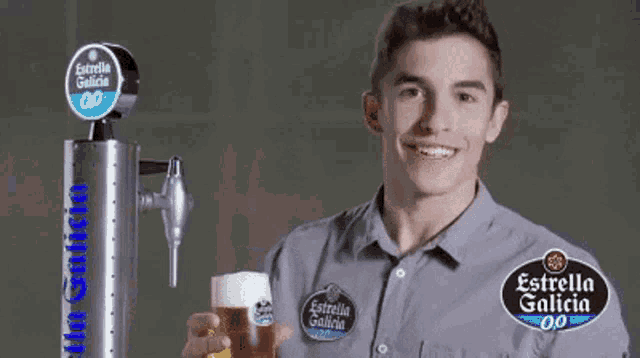 a man holds a glass of estrella galicia beer in front of a beer tap
