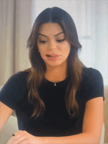 a woman wearing a black t-shirt and a necklace is making a funny face