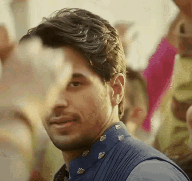 a close up of a man 's face with a crowd of people in the background .