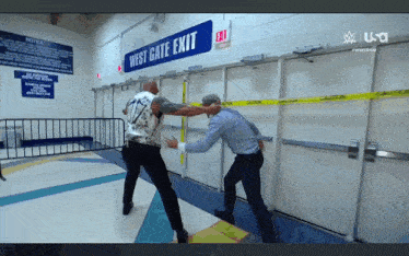 two men are fighting in a hallway with a sign that says west gate exit