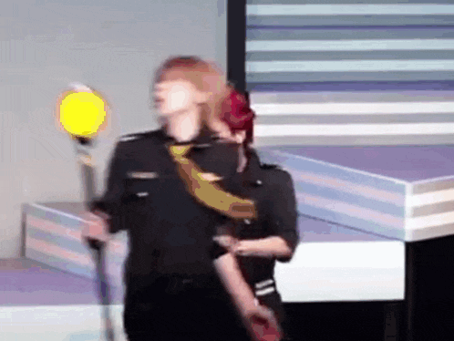 a man in a police uniform is dancing on a stage while holding a light .
