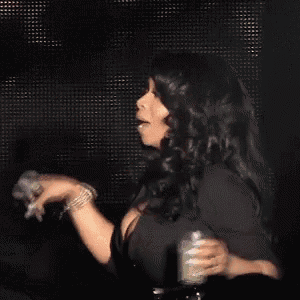 a woman is singing into a microphone on stage in front of a crowd .