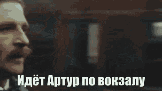 a close up of a man 's face with the words " идет артур по вокзалу " above him