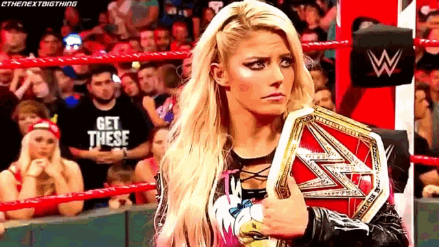 a woman in a wrestling ring is holding a championship belt .