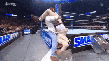 a man is being lifted in the air by another man in a wrestling ring