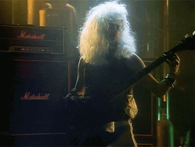 a man plays a guitar in front of a marshall amplifier