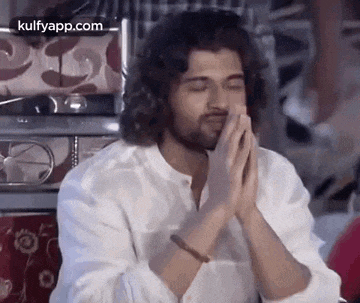 a man in a white shirt is praying with his hands together .