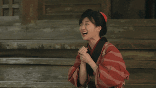 a woman wearing a red and white striped kimono is clapping her hands